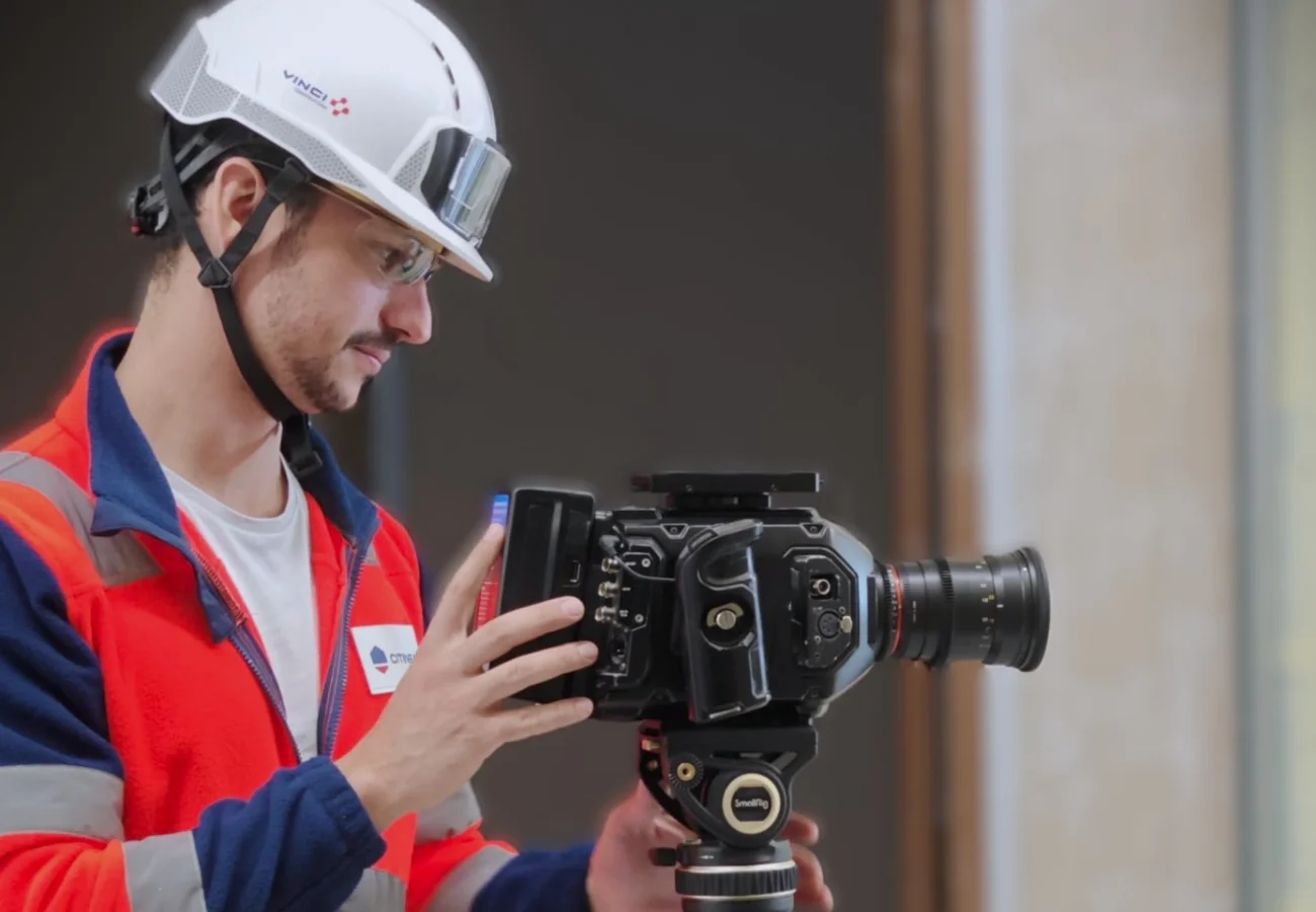 Axel Milon filmant sur un chantier, casque et gilet haute visibilité